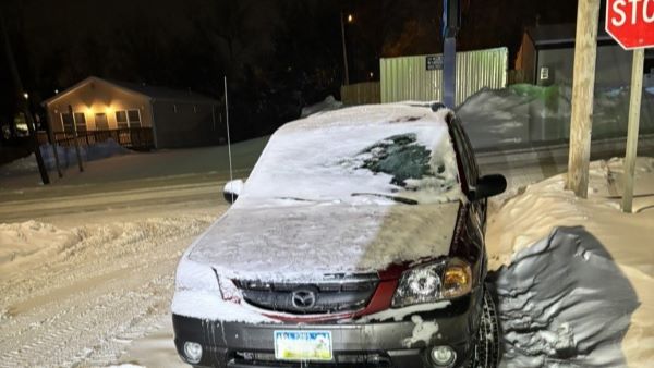 Snow covered car at stop sign