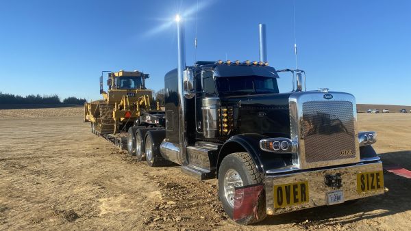 Large tractor on trailer behind heavy duty truck