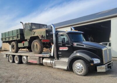 Military truck on flatbed tow truck