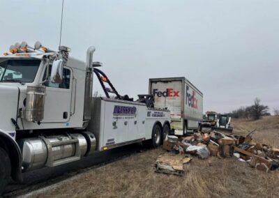 Heavy duty tow truck with damaged FedEx Trailer