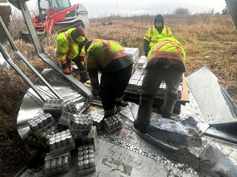 Load Recovery Cleanup Four people cleaning up flats of cans in back of damaged truck