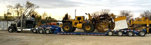 Heavy construction equipment and machine on lowboy trailer behind semi