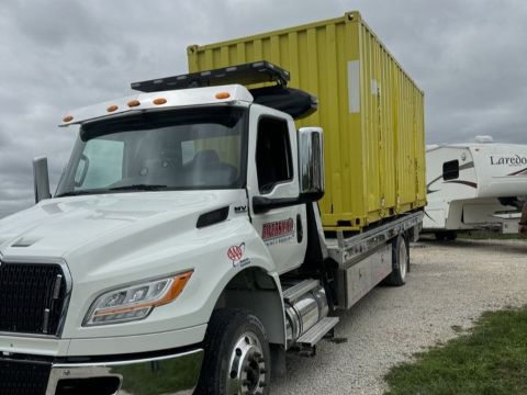 Yellow container on back of flat bed tow truck