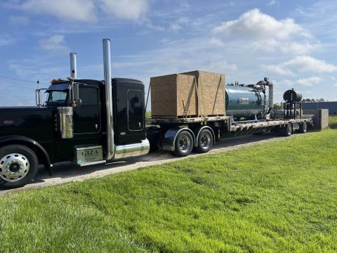 Heavy equipment on back of trailer pulled by semi